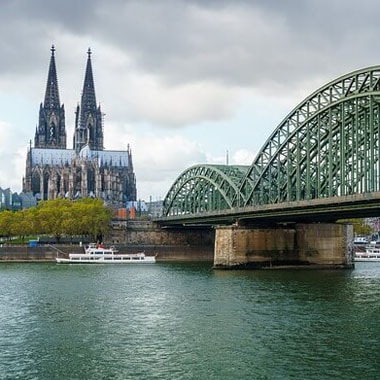 Vista de rio com ponte de aço ao lado direito e catedral ao fundo.